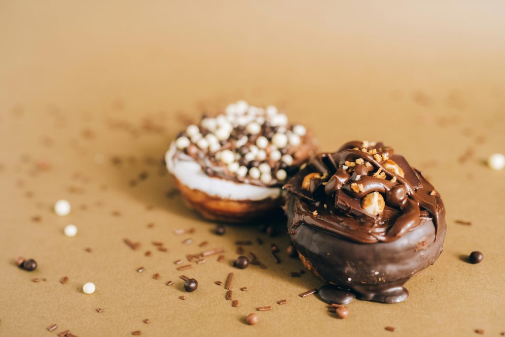 Tasty chocolate-covered donuts topped with sprinkles on a textured surface, perfect for sweet cravings.
